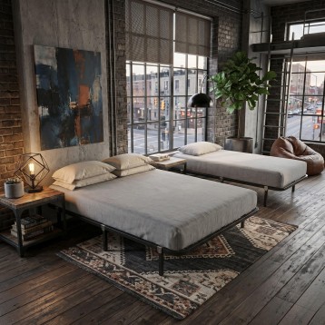 Cama nido con estructura metálica negra y colchones grises en dormitorio estilo loft industrial con ventanales