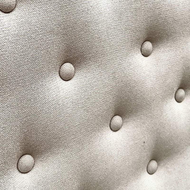 Detalle de tapizado beige claro con botones decorativos hundidos y textura de tejido natural