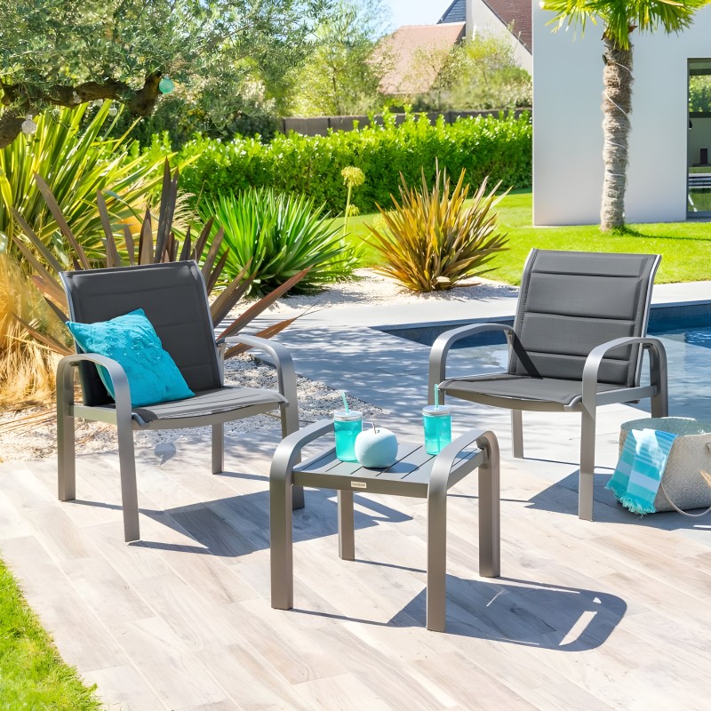 Conjunto de jardín con dos sillones grises y mesa baja en ambiente de terraza junto a piscina