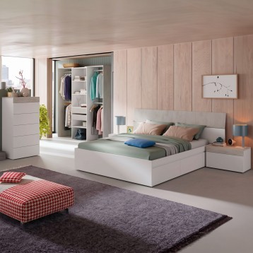 Dormitorio con cama blanca y armario abierto de madera clara. Ambiente completo con mesitas de noche y pared de madera natural