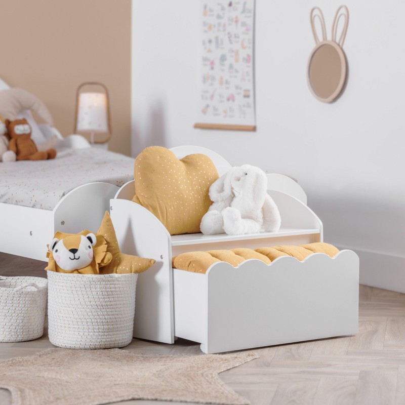 Baúl infantil blanco con formas onduladas y almohadas beige y blancas en dormitorio infantil