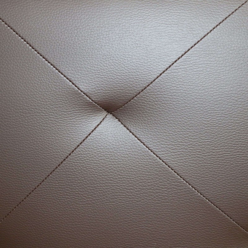 Detalle de tapizado de cuero gris con costuras en patrón geométrico diagonal