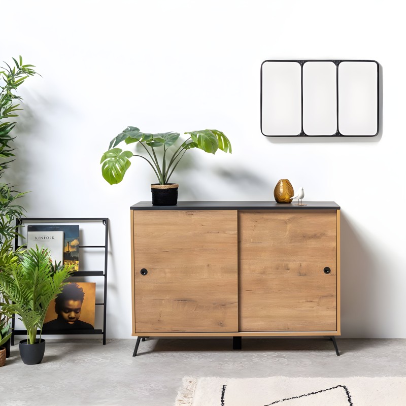Aparador madera clara con puertas correderas y encimera negra en ambiente de salón con plantas y espejo de pared