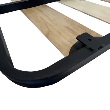 Cama con estructura metálica negra y tablero de madera clara con detalles de montaje visible