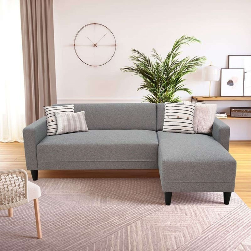 Sofá seccional gris con chaise longue y cojines decorativos en ambiente de sala estar