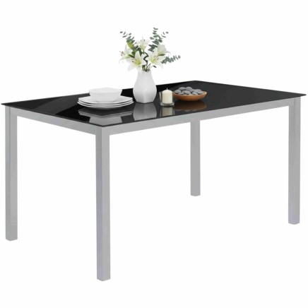 Mesa de comedor rectangular con tapa negra y patas grises metalizado decorada con vajilla y flores