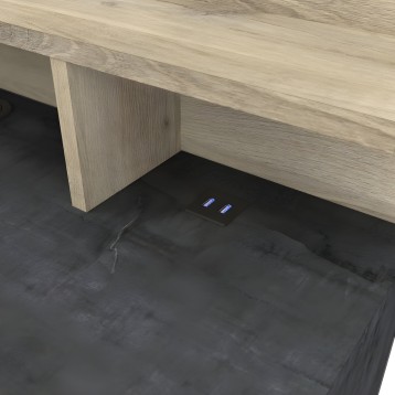 Escritorio con tablero en madera clara y base de madera con detalles de tomas de corriente integradas en la superficie