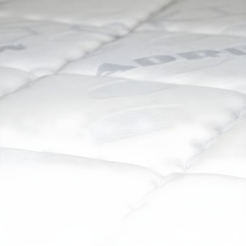 Detalle de colchón acolchado blanco con superficie mullida y costuras decorativas