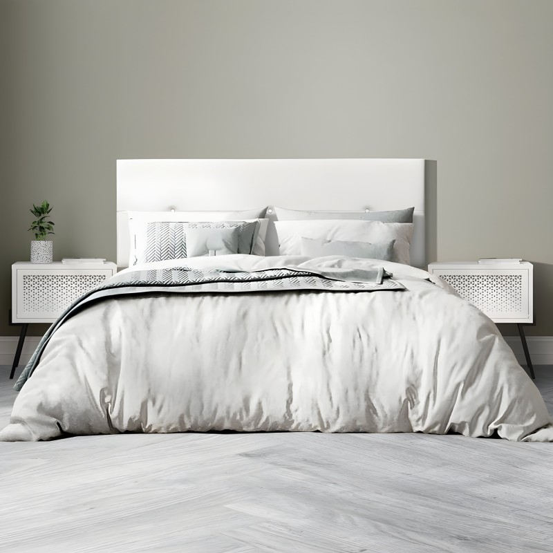 Cama matrimonial con cabecero tapizado blanco y mesitas laterales blancas perforadas en ambiente dormitorio