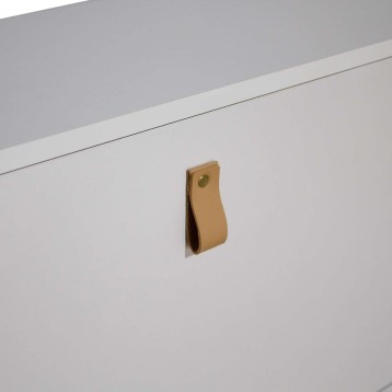 Detalle de tirador de cuero natural en tono camel con remache dorado en mueble blanco