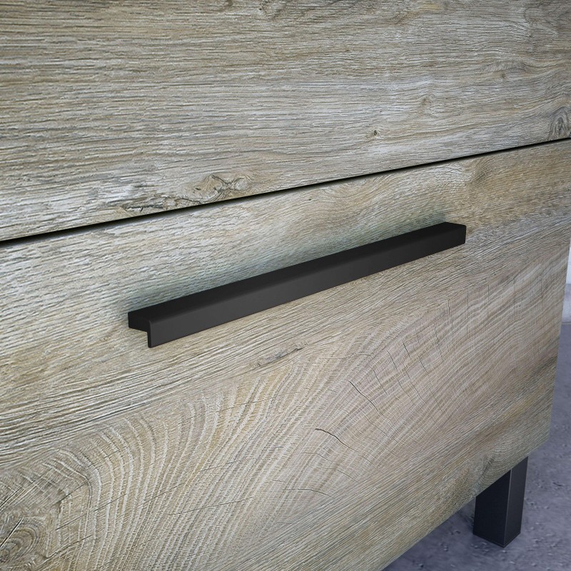 Detalle de tirador negro en cajón de madera clara con acabado texturizado y patas metálicas oscuras
