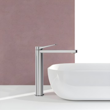 Grifo de baño monocomando alto en cromo pulido junto a lavamanos blanco en ambiente de baño moderno