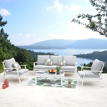 Conjunto de sofá y sillones de aluminio blanco con cojines grises en terraza con vistas al lago
