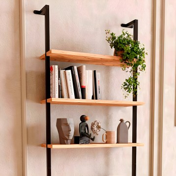 Estantería de pared con tres estantes de madera natural y estructura metálica negra decorada con libros y plantas