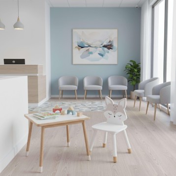 Silla infantil con forma de conejo blanco y patas de madera en ambiente de sala de juegos moderna