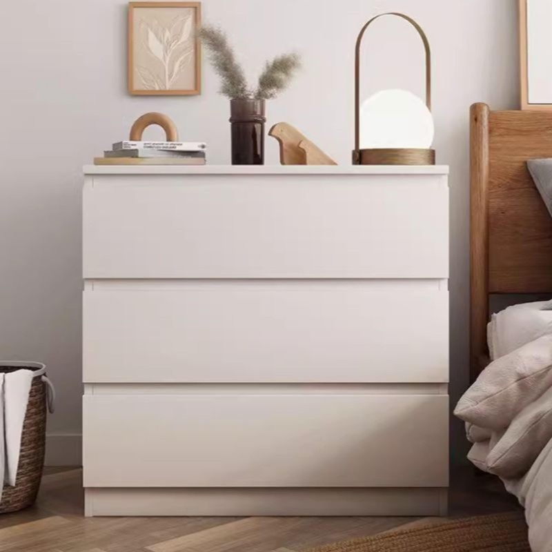 Cómoda blanca con tres cajones y encimera decorada con lámpara de esfera y elementos de madera en dormitorio