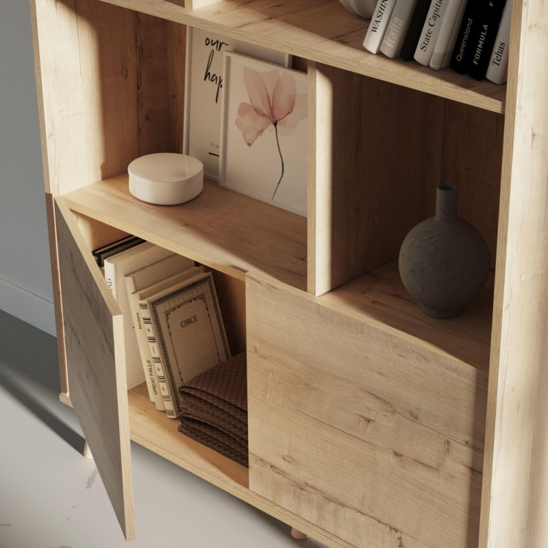 Estantería de madera clara con compartimentos abiertos y puerta inferior decorada con libros y accesorios