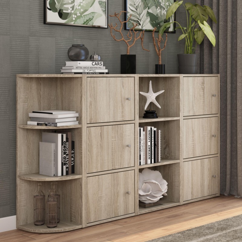 Estantería modular en madera clara con puertas y compartimentos abiertos. Detalles decorativos y libros en ambiente.