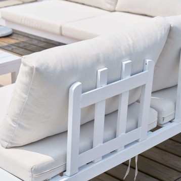 Brazo de sofá blanco con cojín beige y estructura de madera en ambiente de terraza