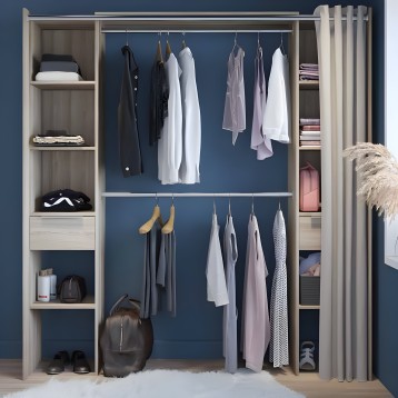 Armario abierto de madera clara con doble barra de colgar y estanterías laterales con ropa blanca y gris organizada contra pared