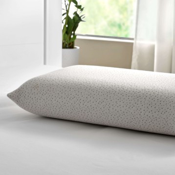 Almohada rectangular en tela gris claro con textura puntillada en ambiente de dormitorio luminoso