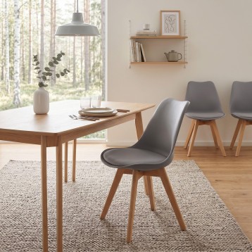 Silla de comedor con asiento acolchado gris y patas de madera natural en ambiente de comedor