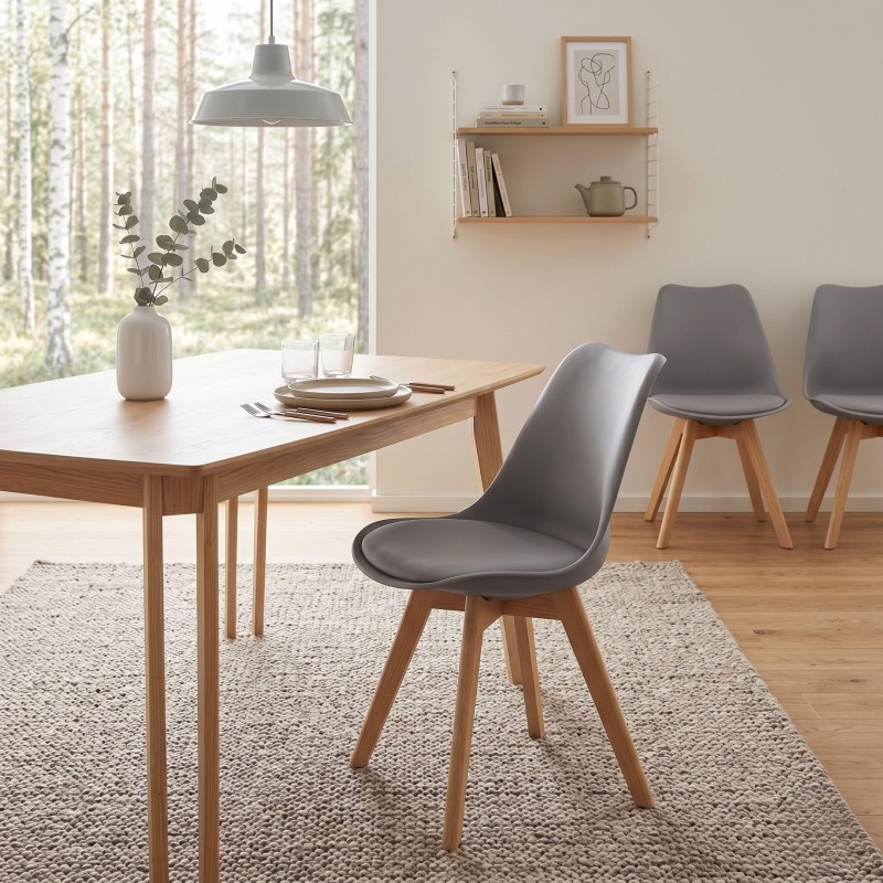Silla de comedor con asiento acolchado gris y patas de madera natural en ambiente de comedor