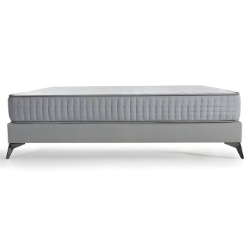 Cama con somier tapizado gris y colchón acolchado blanco patas de madera negra vista lateral