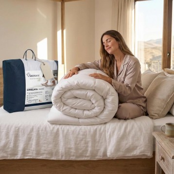 Edredón blanco enrollado sobre cama con mujer tocándolo y embalaje azul marino visible en ambiente de dormitorio