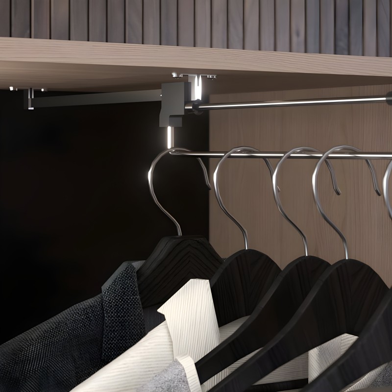 Percha de metal cromado con ganchos curvos en ángulo sobre barra de aluminio en armario minimalista con iluminación integrada y 