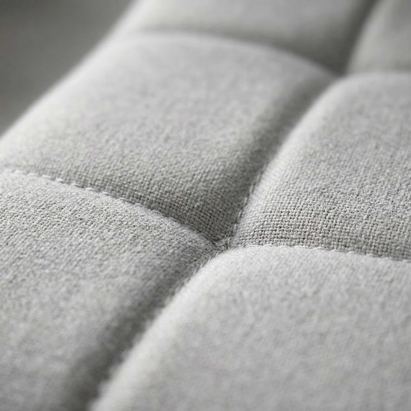 Detalle de tapizado en tela gris claro con costuras y pliegues de sofá o sillón